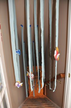 some paper streamers are hanging from the ceiling in front of a staircase with wooden steps