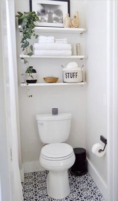 a white toilet sitting in a bathroom next to a shelf