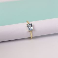 a ring with an aqua blue topazte sits on a white piece of paper