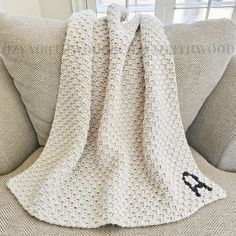 a white crocheted blanket sitting on top of a couch next to a window