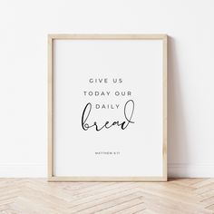 a white framed poster with the words give us today our daily bread written in cursive font