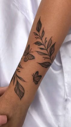 a woman's arm with butterflies and leaves tattooed on the left side of her arm