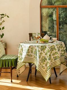 a dining room table with green and white cloths on it, next to a potted plant