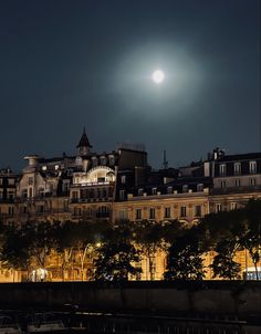 the full moon shines brightly over an old city at night