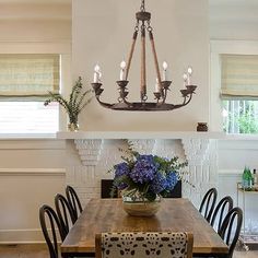 a dining room table with chairs and a chandelier hanging from it's ceiling