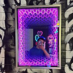 a man taking a selfie in front of a mirror with neon lights on it