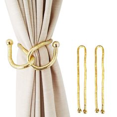 curtain clips with gold colored metal handles attached to the side of a drapesed window