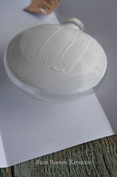 a white cake sitting on top of a wooden table next to a piece of paper