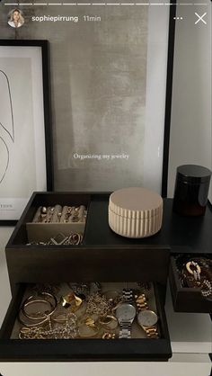 an assortment of jewelry sits on display in a black and white box next to a framed photograph