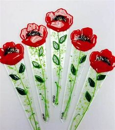 four red flowers are sitting on top of some green stickers with sprinkles