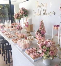 a table with pink flowers and cupcakes on it