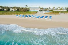 an aerial view of beach chairs and umbrellas on the sand with ocean waves in foreground