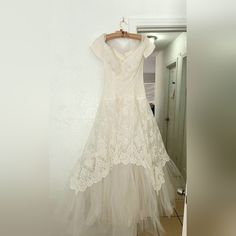 a white dress hanging on a wall next to a door with a mirror in the background