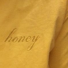 the word honey written in cursive writing on a yellow shirt