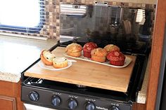 some muffins are sitting on a cutting board in front of the stove top