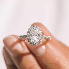 a woman's hand holding an engagement ring with a diamond in the center and two rows of diamonds on each band