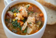 a white bowl filled with soup next to some bread