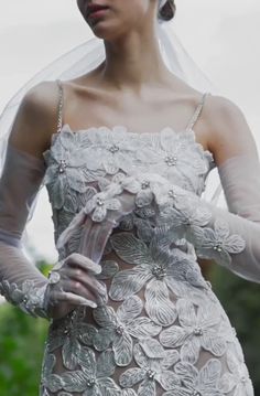 a woman wearing a veil and dress with flowers on it