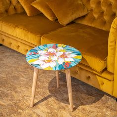 a yellow couch sitting next to a wooden table on top of a carpeted floor