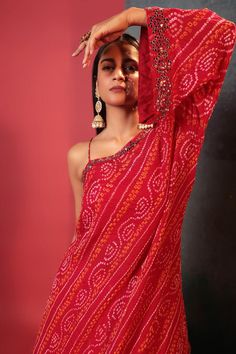 Red one shoulder padded kurta with bandhani woven motifs and mirror embellished neckline. Paired with cami top and dual toned crushed skirt with attached cancan.
Components: 3
Pattern: Woven, Embellished
Type Of Work: Bandhani, mirror
Neckline: Asymmetric
Sleeve Type: One shoulder sleeve
Fabric: Pure Georgette, Silk
Color: Red
Other Details: 
High low hem of kurta
Length:
Kurta: 36 inches
Skirt: 42 inches
Occasion: Sangeet - Aza Fashions Bollywood Style One Shoulder Saree For Festive Occasions, Bollywood Style One-shoulder Saree For Festive Occasions, Bollywood One Shoulder Saree For Festive Occasions, Bollywood Style One-shoulder Festive Saree, Bollywood Style One Shoulder Saree, Bohemian Red Pre-draped Saree For Festive Occasions, Traditional One-shoulder Festive Sets, Festive Traditional One-shoulder Set, Festive One-shoulder Saree