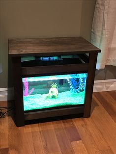 a fish tank sitting on top of a hard wood floor next to a wooden table