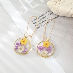 a pair of earrings with flowers in them sitting on top of a piece of paper