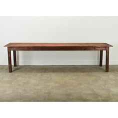 a large wooden table sitting on top of a cement floor next to a white wall