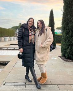 two women standing next to each other on a sidewalk