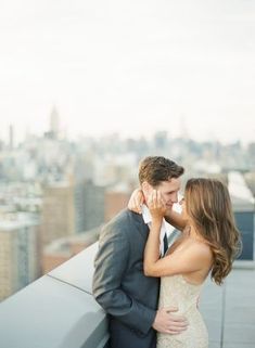 a bride and groom kissing on top of a building in new york city, ny