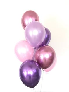 a bunch of purple and pink balloons are in the shape of a pyramid on a white background