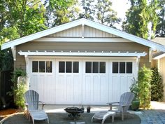 two lawn chairs sitting in front of a garage with a fire pit on the driveway