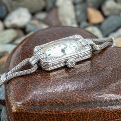 This old platinum and diamond watch features old European and single cut diamond accents. The face of the watch is signed Marcus & Co, and the movement is signed Cresarrow W. Co. The movement has 18 jewels and 3 adjustments. The watch is on a 10k white gold diamond band that is finished with a white metal clasp. The back case of the watch has a monogram of "H.V.B.J." As of this writing, the watch currently ticks and can keep time for at least a few hours, but that could change at any moment. We do not offer any warranty on watch movements. Antique Platinum Jewelry And Watches As Gifts, Antique Platinum Silver Jewelry And Watches, Antique Platinum Evening Watches, Vintage Platinum Diamond Watch With Polished Finish, Antique Platinum Diamond-studded Watch, White Gold Diamond Band, Art Deco Watch, Diamond Watch, Women Wrist Watch