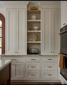 a kitchen with white cabinets and gold pulls on the cupboards is pictured in this image