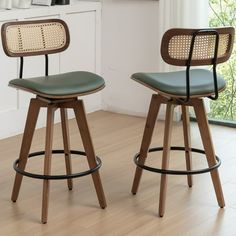 two wooden barstools with green leather seats in front of a white kitchen counter