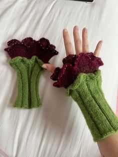 a person's hand wearing green knitted gloves with red flowers on them, resting on a bed