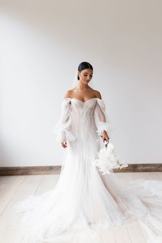 a woman in a wedding dress standing on a wooden floor