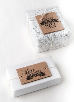 two white gift boxes tied with twine and brown paper are sitting next to each other