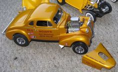 a yellow toy car with an engine on the back is parked next to other toys