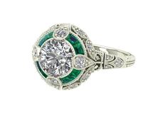 an antique style diamond and emerald engagement ring with diamonds on the sides, set in white gold