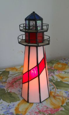 a light that is sitting on top of a flowered table cloth with a lamp in the shape of a lighthouse