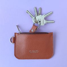 a brown leather key case with two keys in it and a pair of scissors sticking out of the pocket