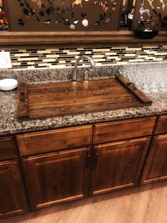 a kitchen sink made out of wood with granite counter tops and backsplash in the background