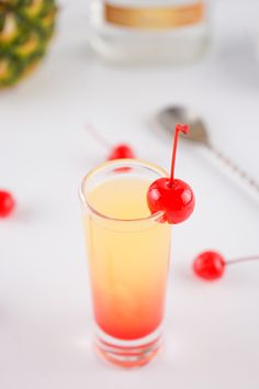 a drink with a cherry garnish on the rim and a pineapple in the background