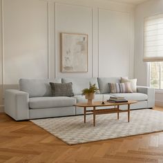 a living room with white walls and wood flooring on the wooden floors, a light blue sectional sofa sits in front of a coffee table