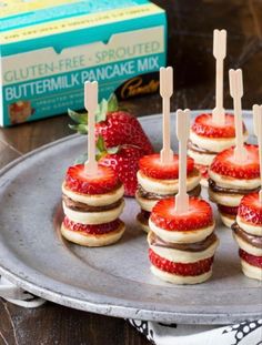 strawberries and chocolate covered cookies are arranged on a plate with toothpicks sticking out of them