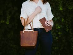 a woman holding a brown purse and wallet