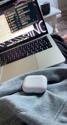 an open laptop computer sitting on top of a bed next to a mouse and coffee cup