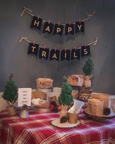 a table topped with lots of cakes and desserts next to a happy trails banner