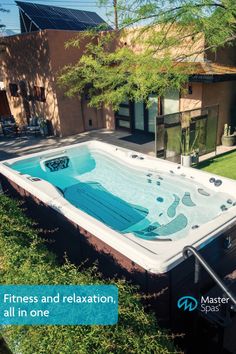 a large hot tub sitting in the middle of a lush green field next to a building