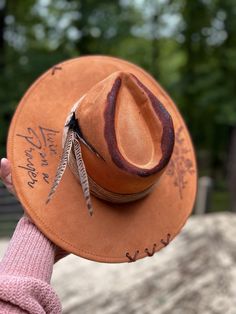 "Livin' on a prayer" handcrafted western wide brim...🤠 Product details: Suede western wide brim/"Livin' on a prayer" quote/Burned flower bundle/suede stitched x's/pheasant feathers/twisted rope hat band. Handmade Western Fedora For Western-themed Events, Artisan Fedora For Western-themed Events, Distressed Bohemian Hat For Festivals, Handmade Country Style Fedora For Western-themed Events, Handmade Wide Brim Fedora For Ranch, Rustic Handmade Ranch Hat, Rustic Handmade Hat Bands For Rodeo, Handmade Rustic Hat Bands For Rodeo, Handmade Rustic Rodeo Hat Bands